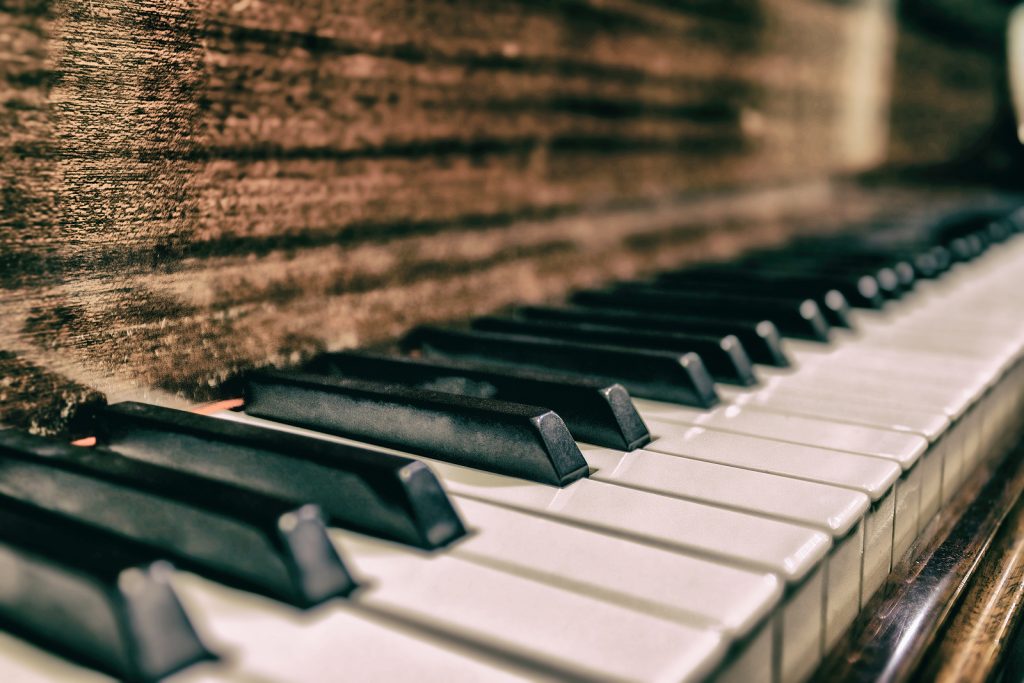Close-up view of piano keys, showcasing the contrast between the black and white keys on a vintage wooden piano, emphasizing texture and detail. The Piano is ready for moving.